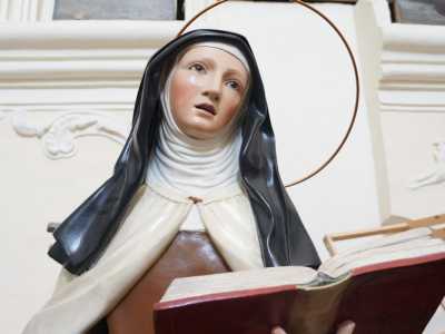 Riconosciamo, incastrata tra banchi rovesciati, la statua lignea di Teresa D�Avila, vestita in abiti monacali, con lo sguardo in contemplazione e un testo sacro aperto nella mano sinistra 